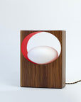 Front view of unlit walnut table lamp with red inner ring and frosted orb bulb