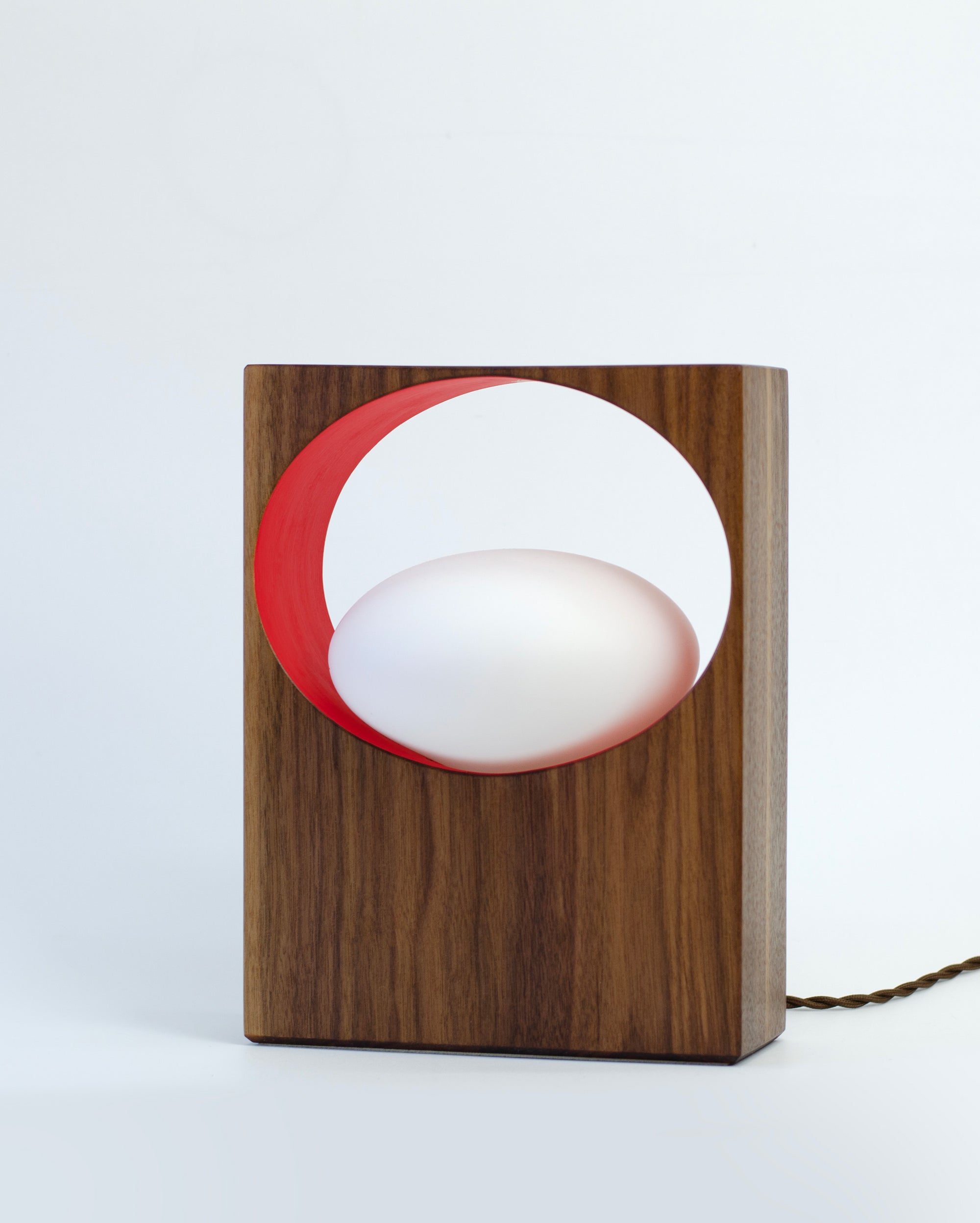 Front view of unlit walnut table lamp with red inner ring and frosted orb bulb