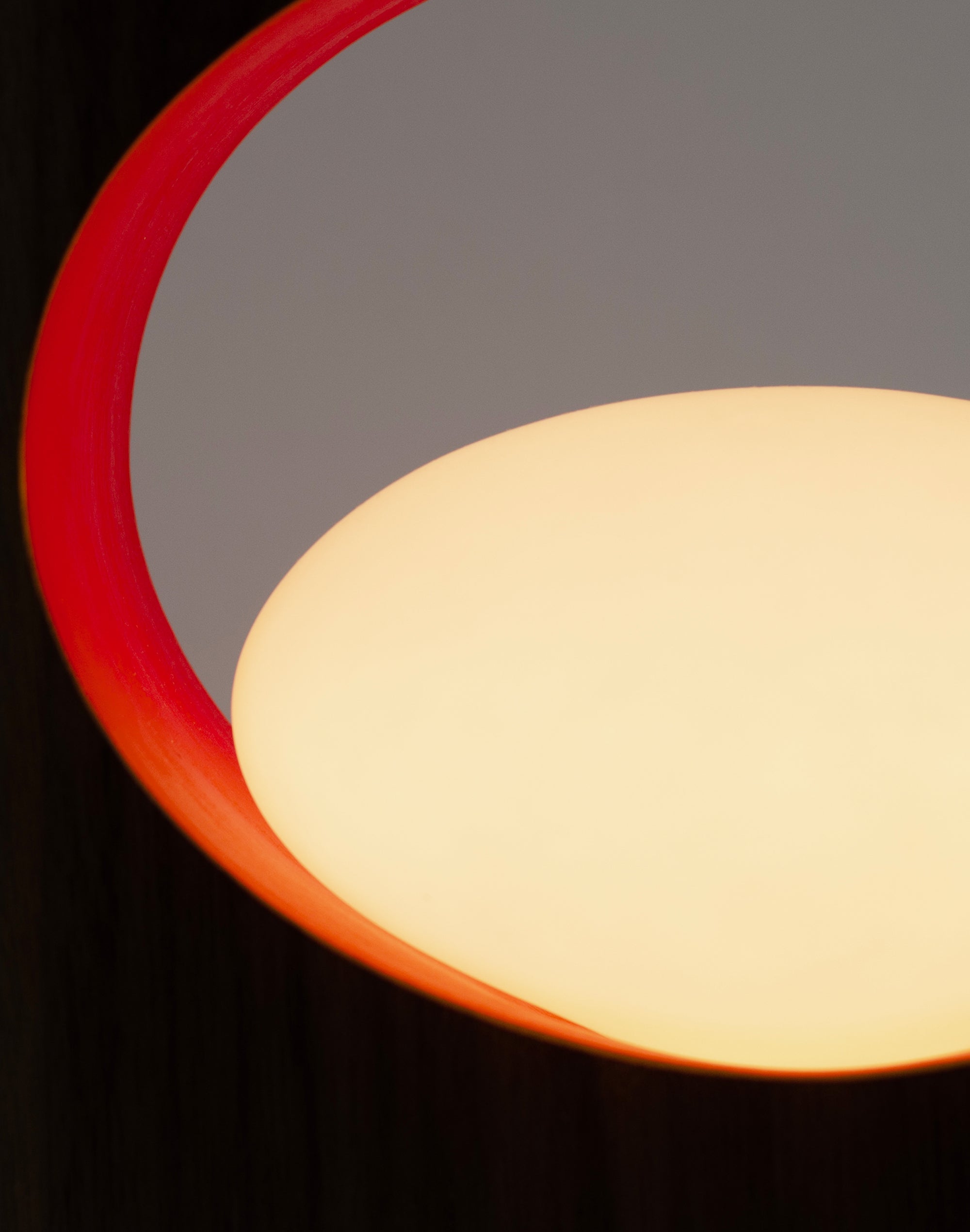 Close-up of walnut table lamp with red inner ring and soft warm glow